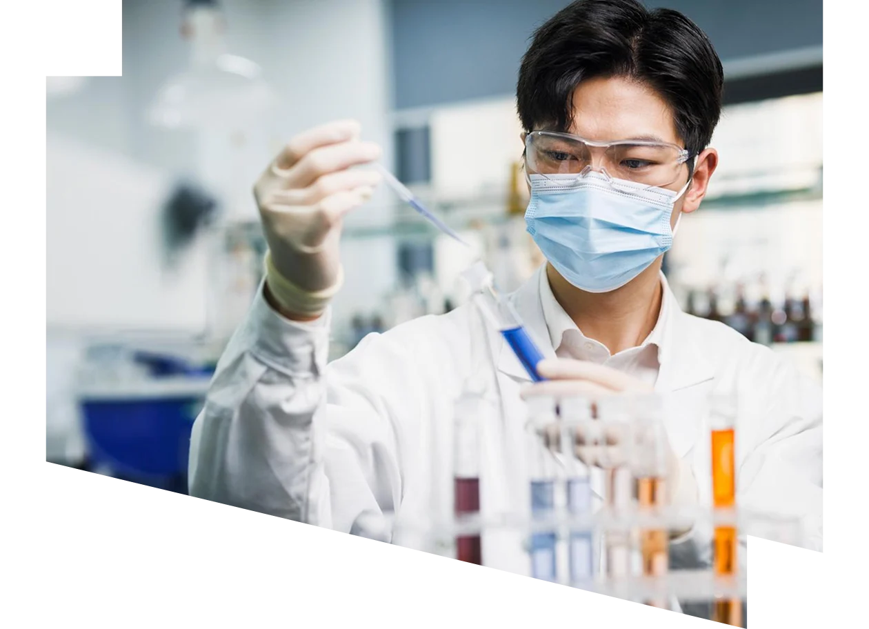 Scientist wearing safety goggles and gloves pipetting a sample into a testtube