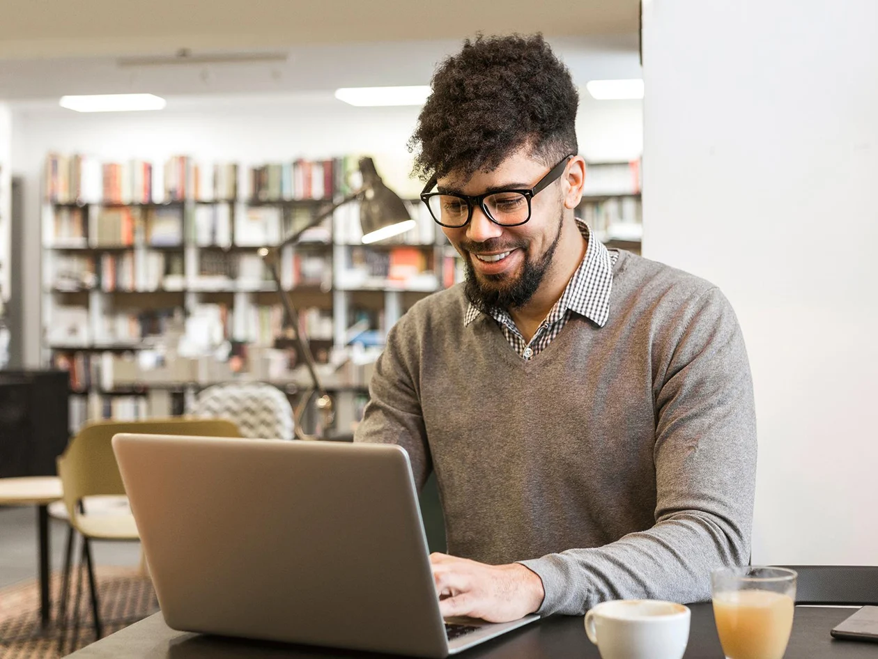 Young man in library on laptop
