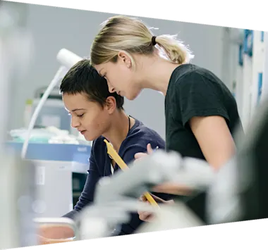 Two women working in the lab and looking down at an object out of frame