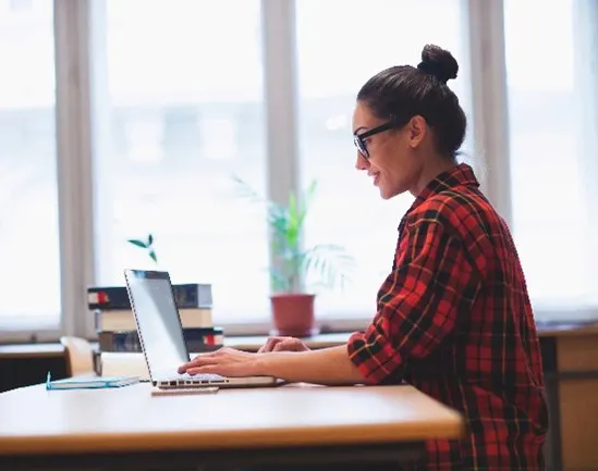 Young woman working at desk next to window