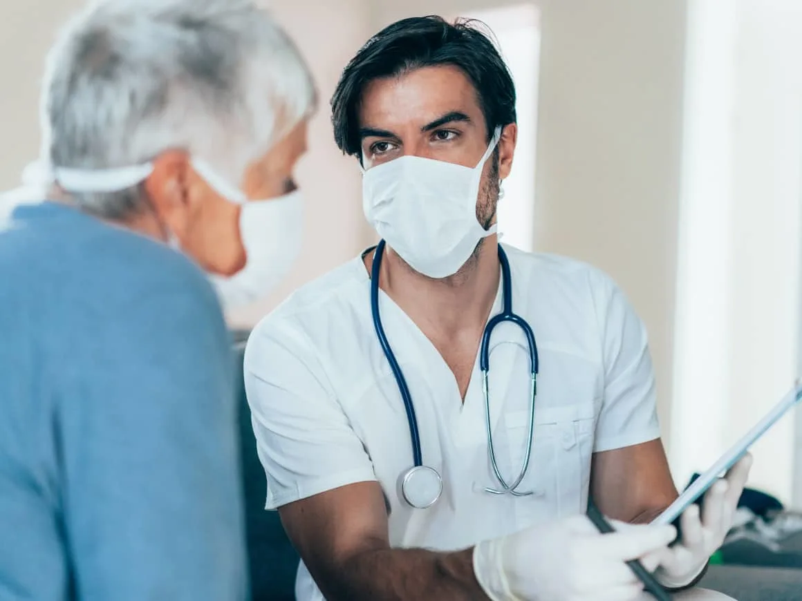 Male doctor elderly patient talking masked Benefit