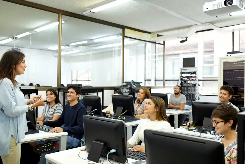 Woman standing in from of a group of students, who are sitting at computers