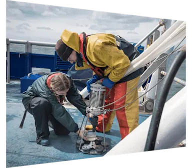 Marine biologist taking plankton samples from net on research ship.