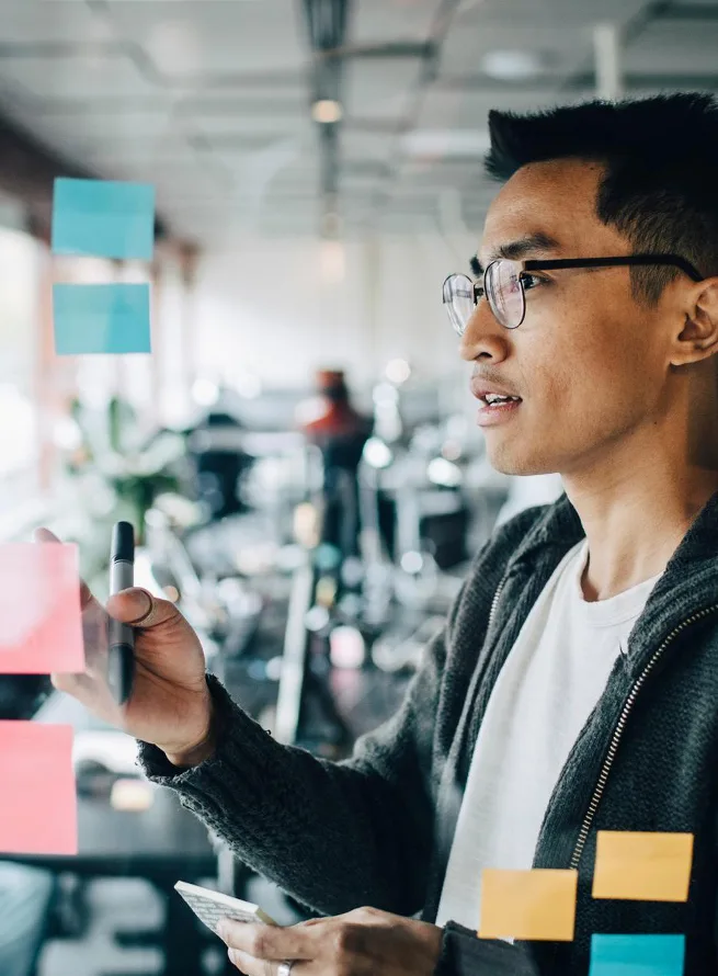 A woman in glasses with a tablet, looking away at the screen.