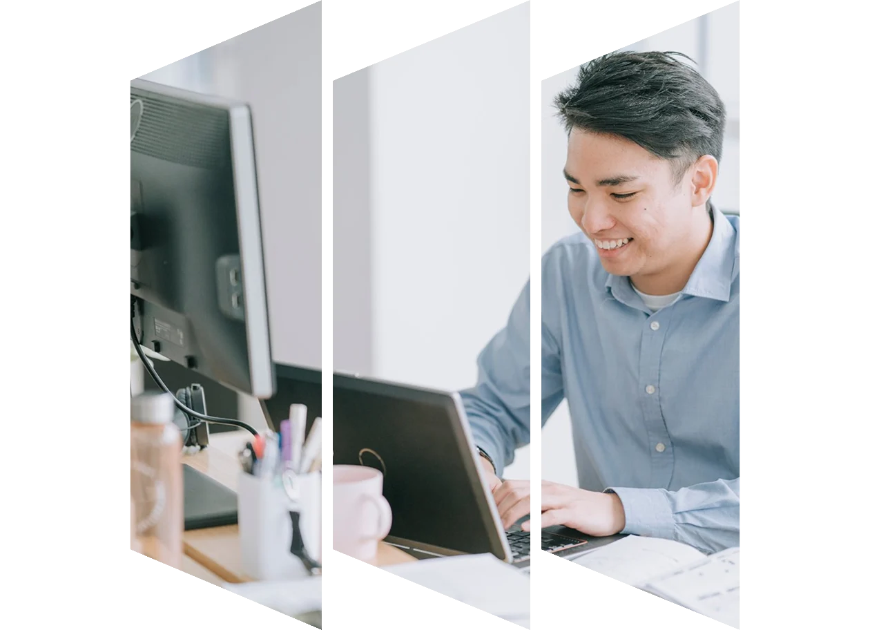 Asian man typing in front of laptop with multiple screen at his work place