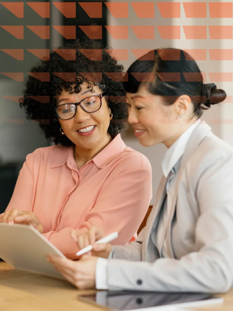 Businesswomen collaborating in office meeting using laptop and documents