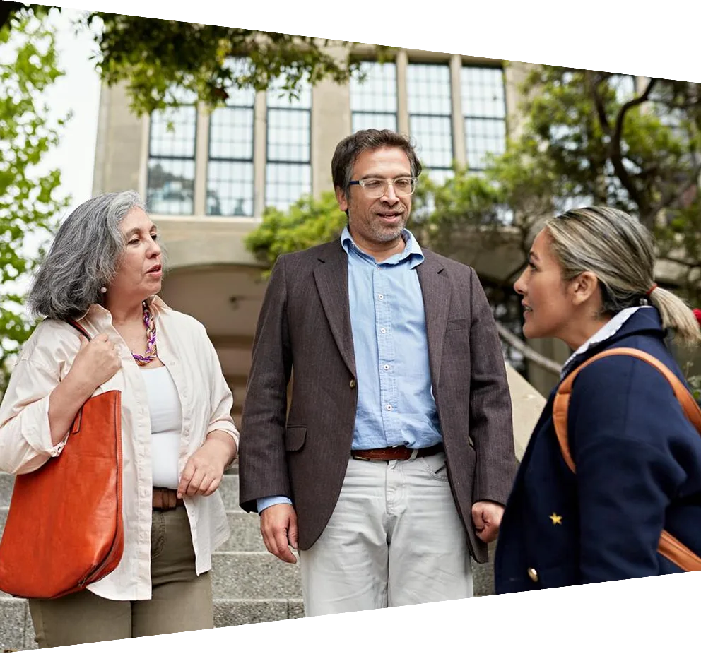 Smiling teachers greet a mature female student at college entrance