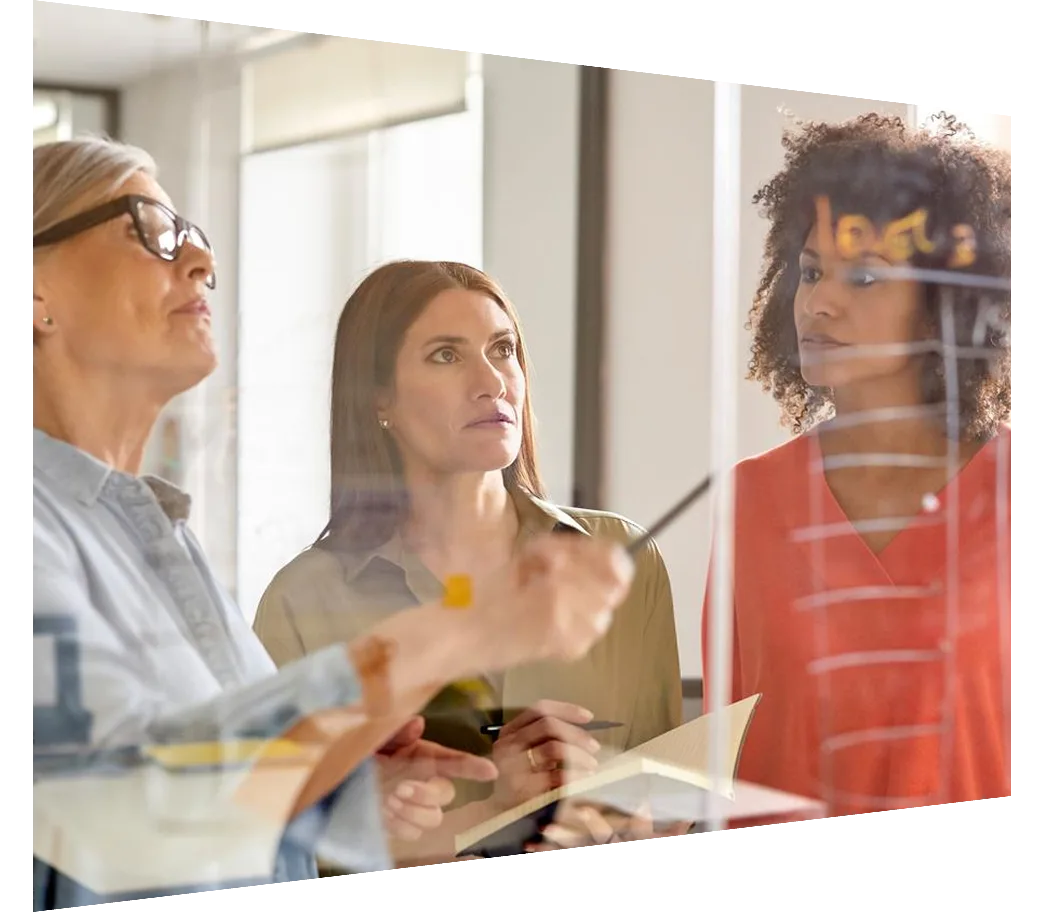 Multi-ethnic businesswomen discussing plan on glass wall