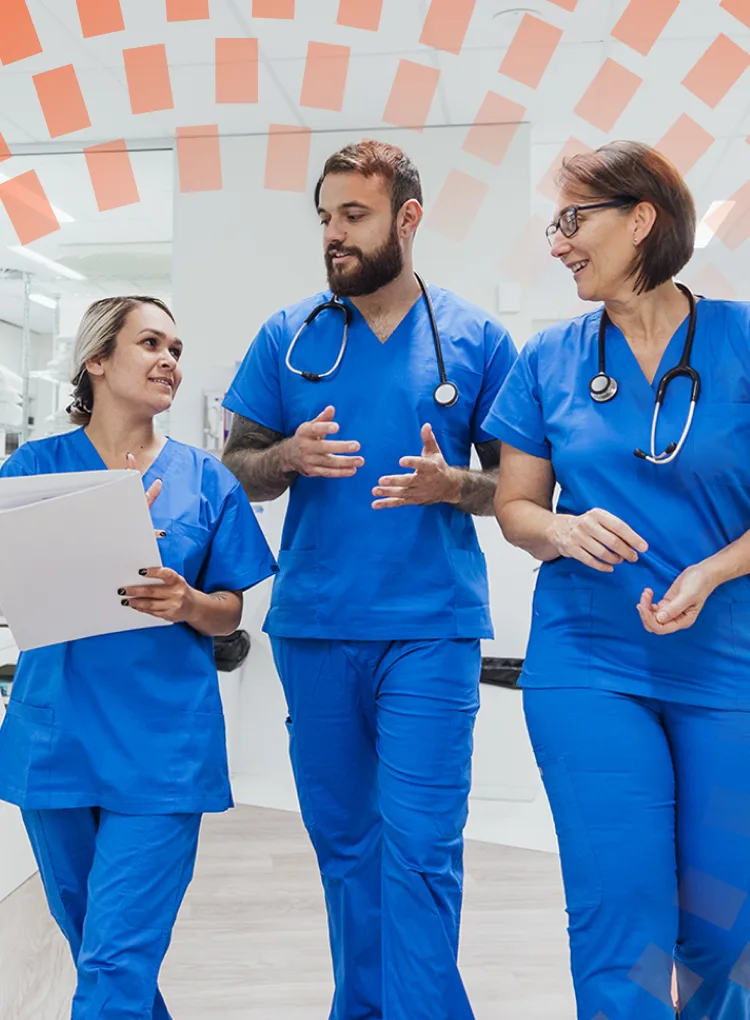 Three healthcare workers walking and talking through a hospital ward