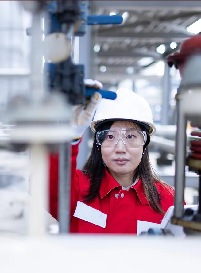 Two men in hard hats and safety vests stand by a power line at night.