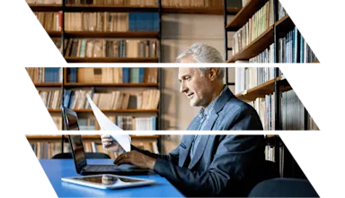 Mature man in suit working at desk in library