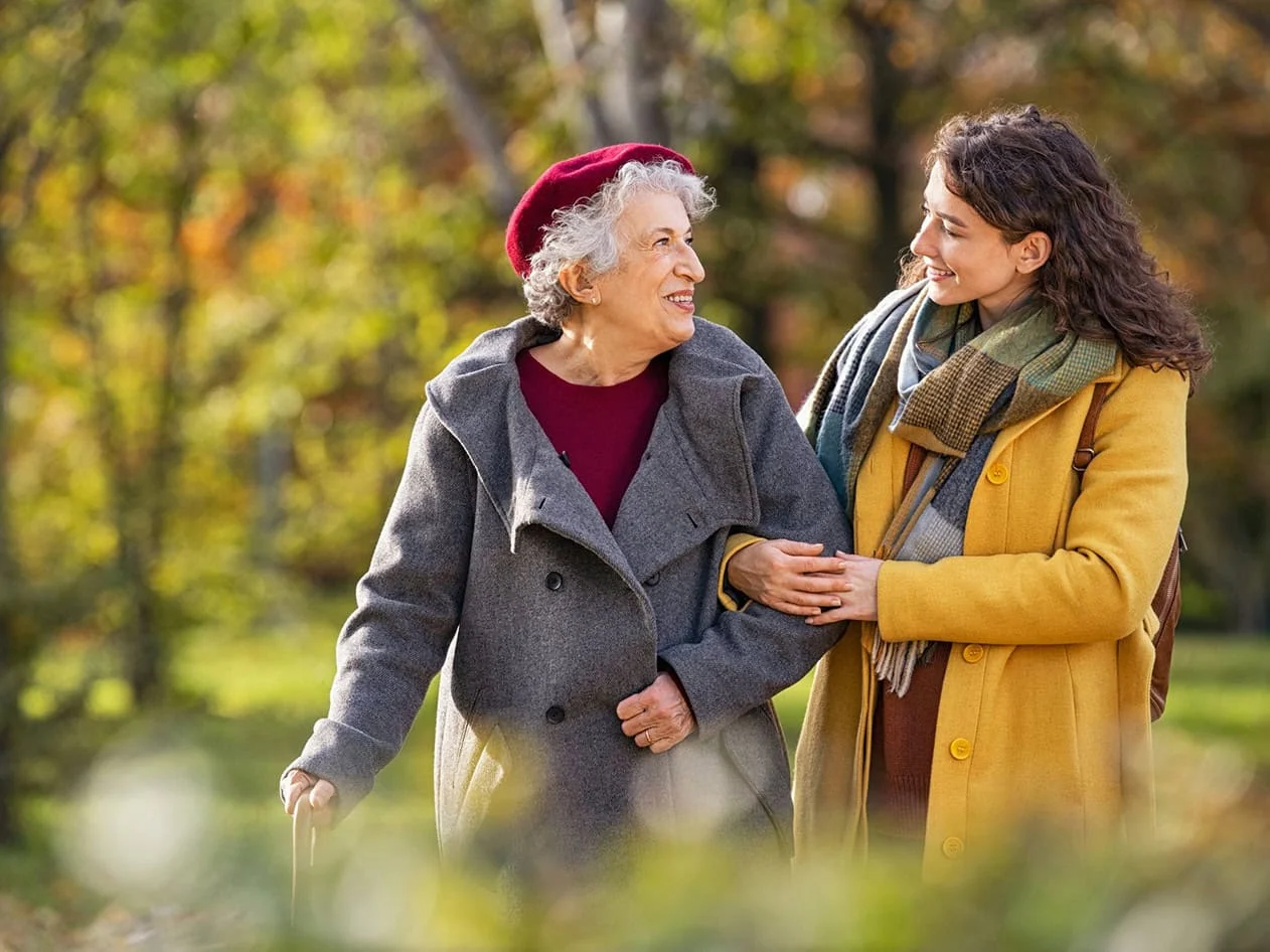 Senior woman walking with granddaughter in park during autumn