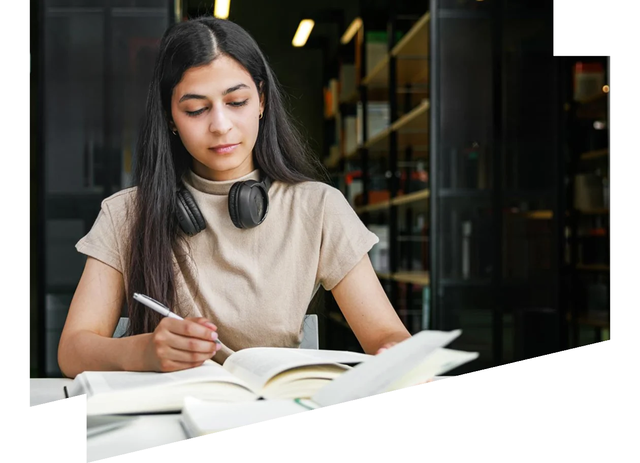 Female student studying with books and a laptop in the library