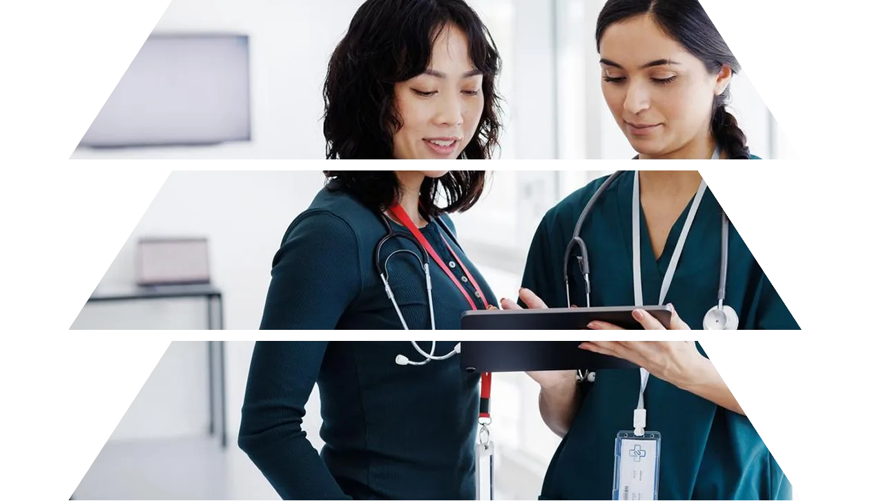 A healthcare worker in scrubs uses a tablet, engaged in a task, in a medical environment.