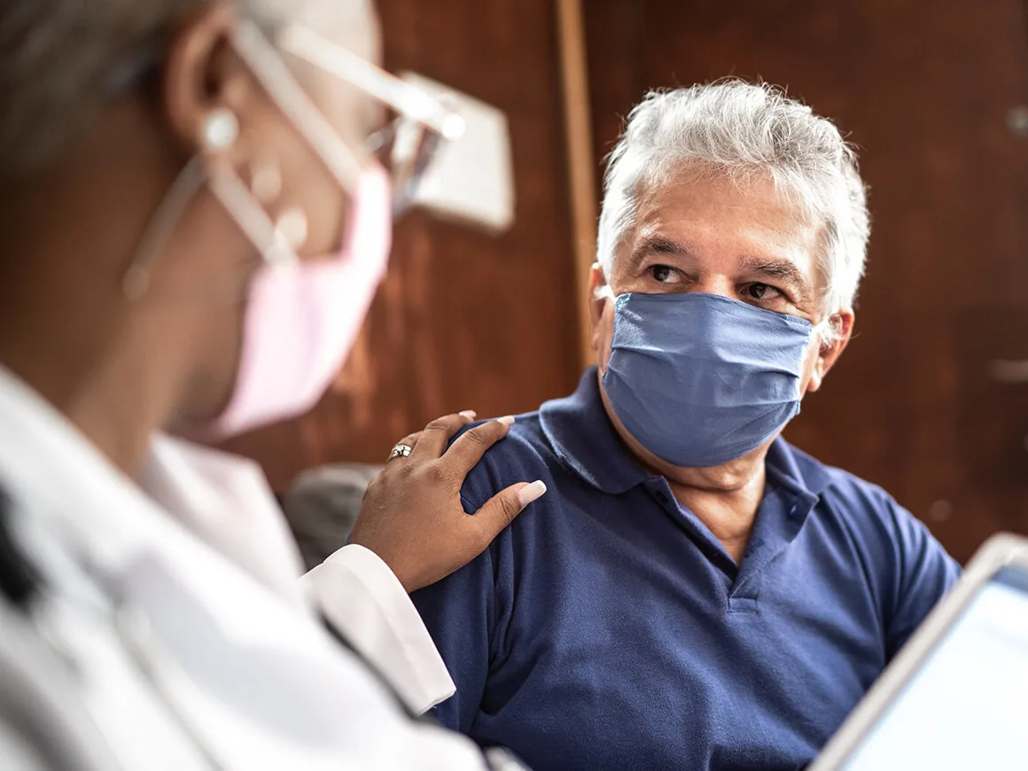 Doctor talking to senior male patient wearing masks