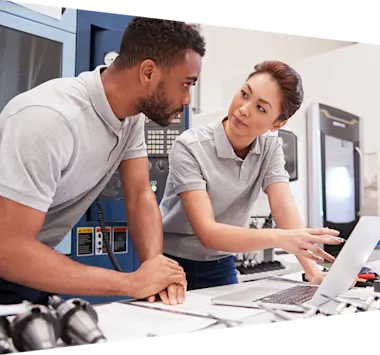 Two students in discussion with chalkboard in background