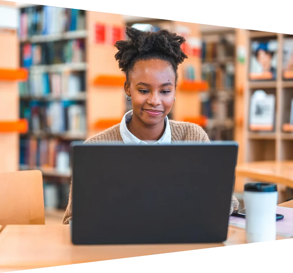 Young Hispanic female student using a laptop in a library