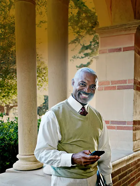 Academic leader standing on campus holding mobile phone