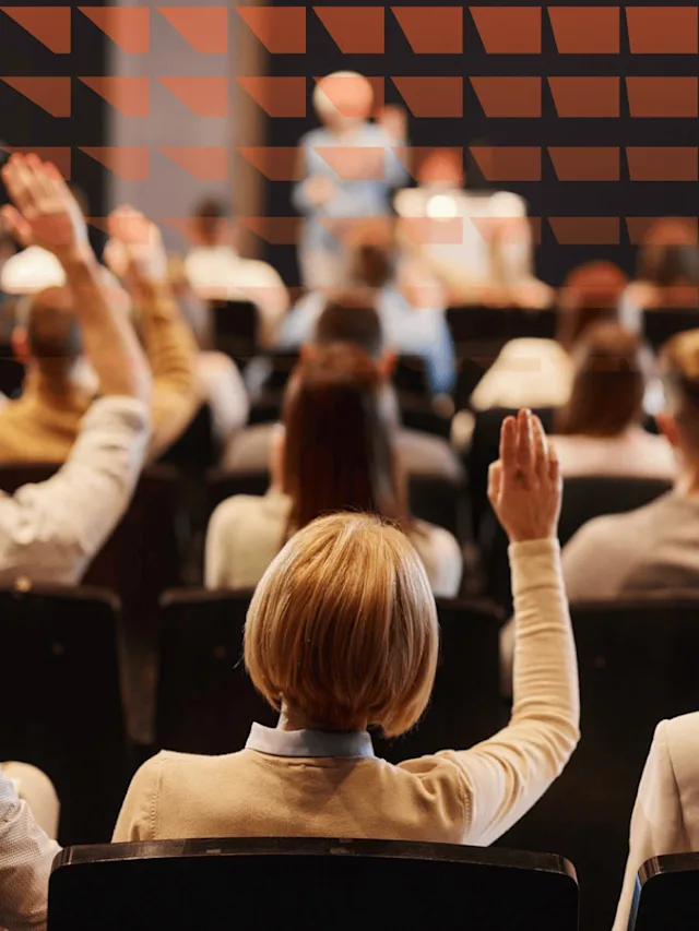 Rear view of large group of people raising their arms to ask questions at press conference