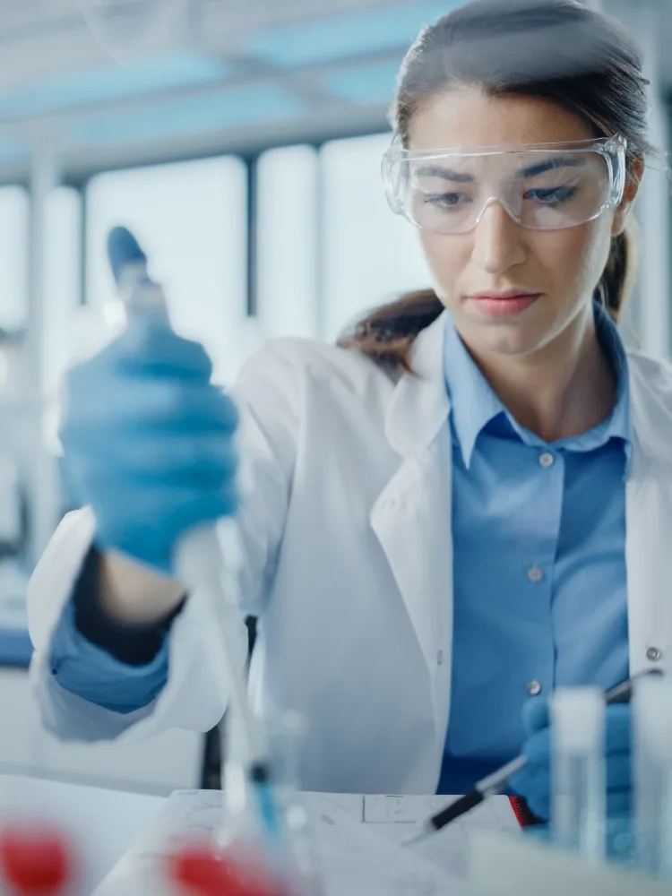Beautiful Female Scientist in Goggles Using Micro Pipette for Test Analysis