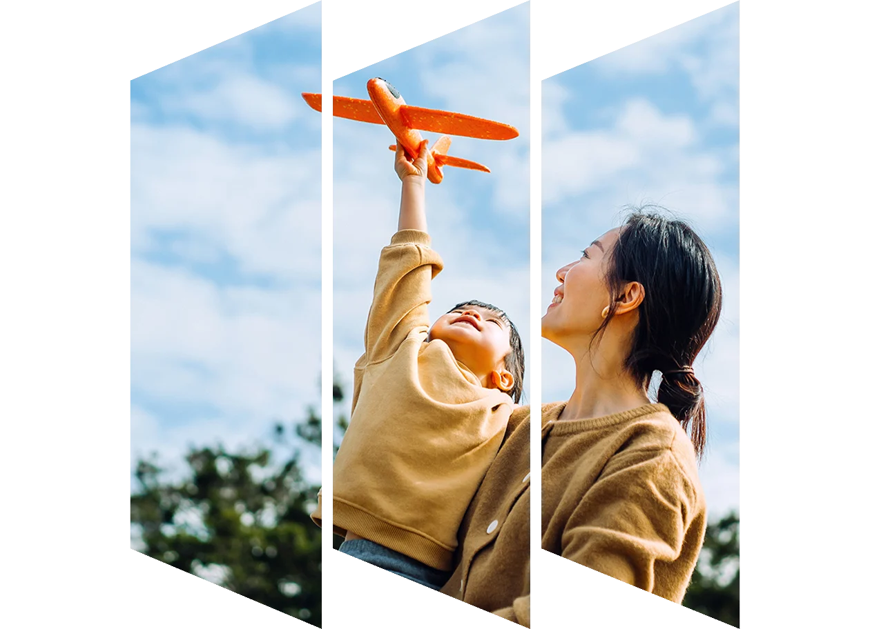 Young Asian mother and daughter playing with a toy airplane outdoors