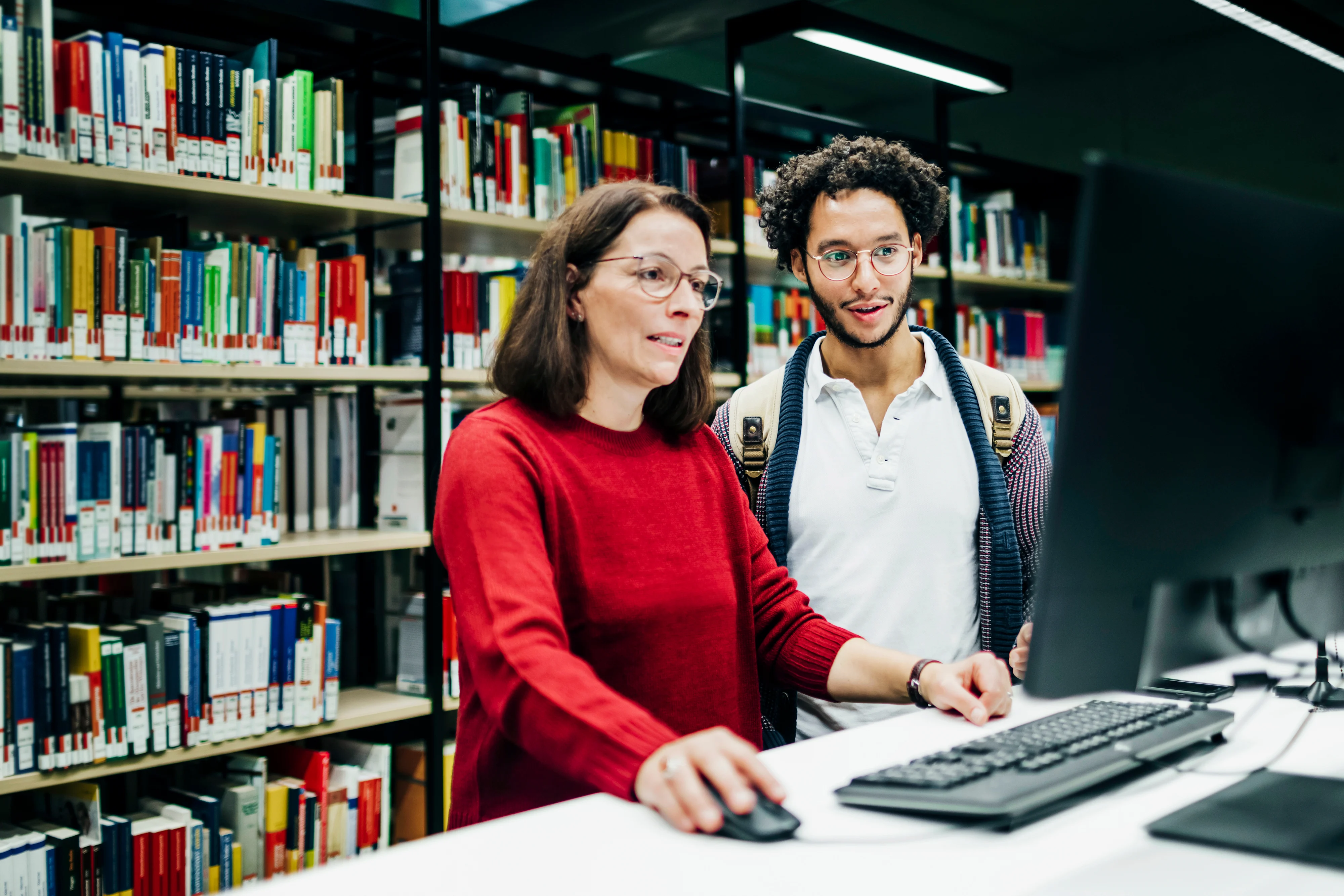 Librarian looking up books on computer for student