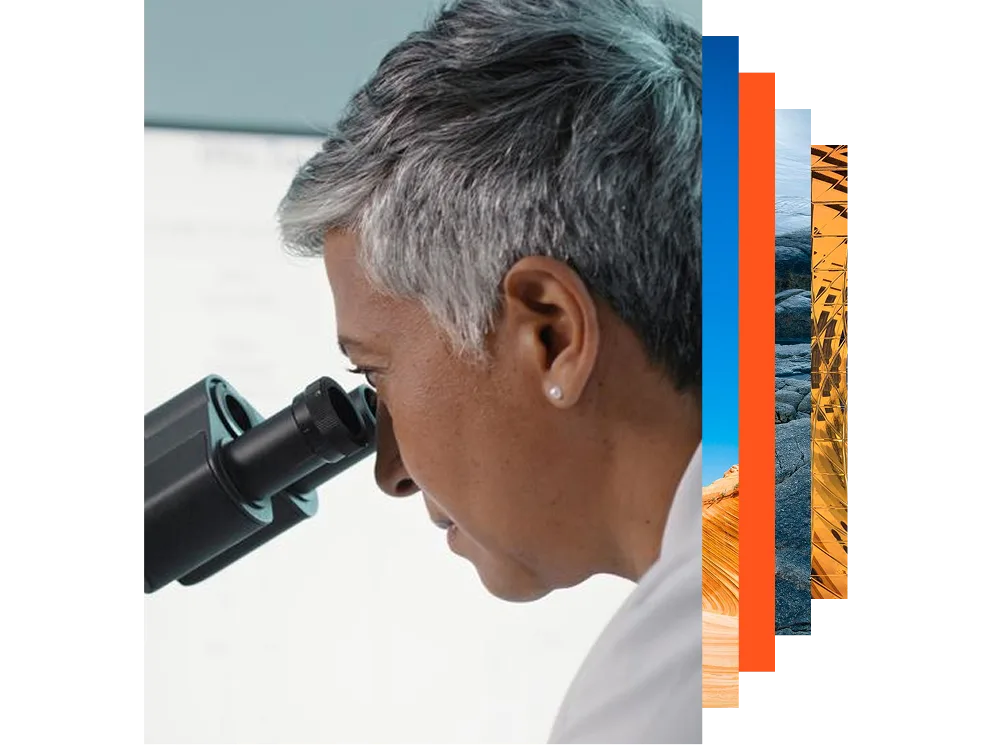 A woman peers intently through a microscope in a laboratory setting.