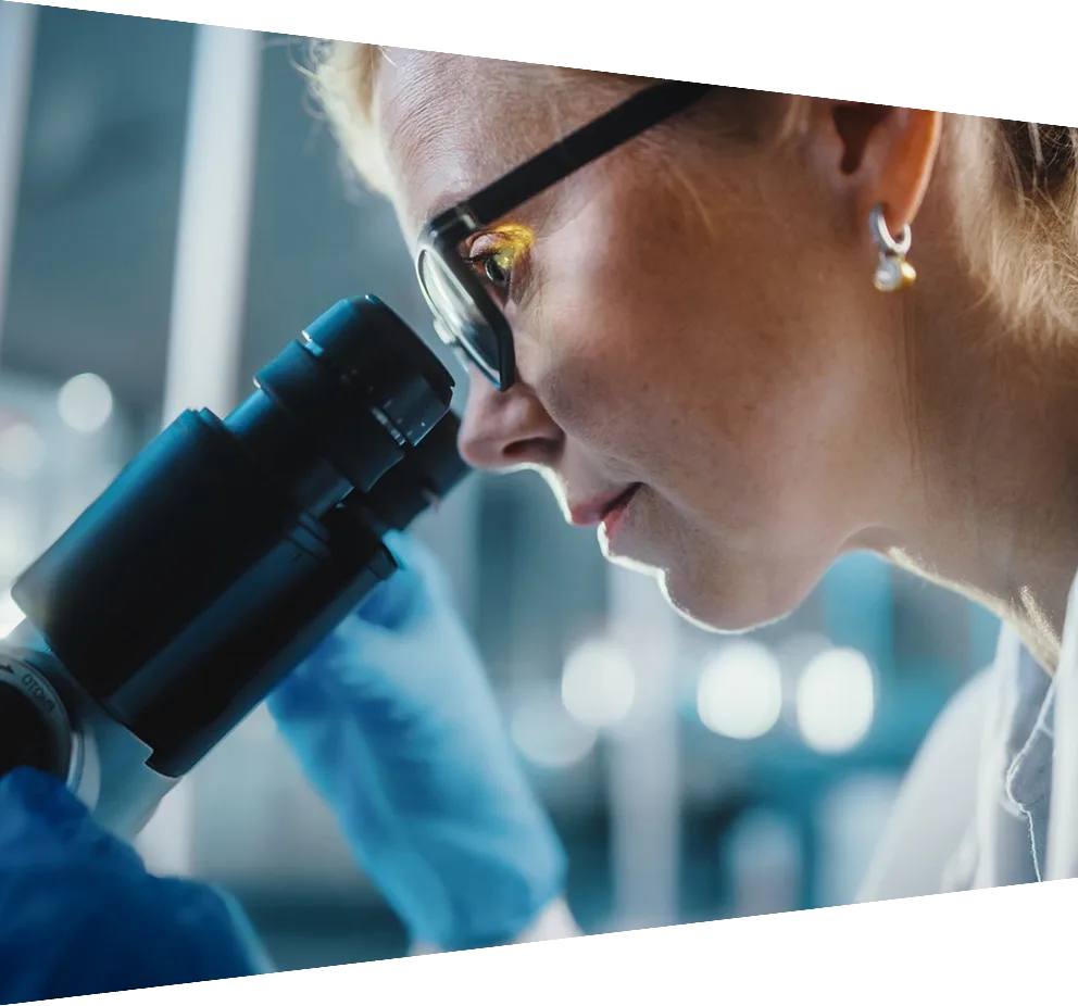 Microbiologist wearing glasses analyzing sample under microscope