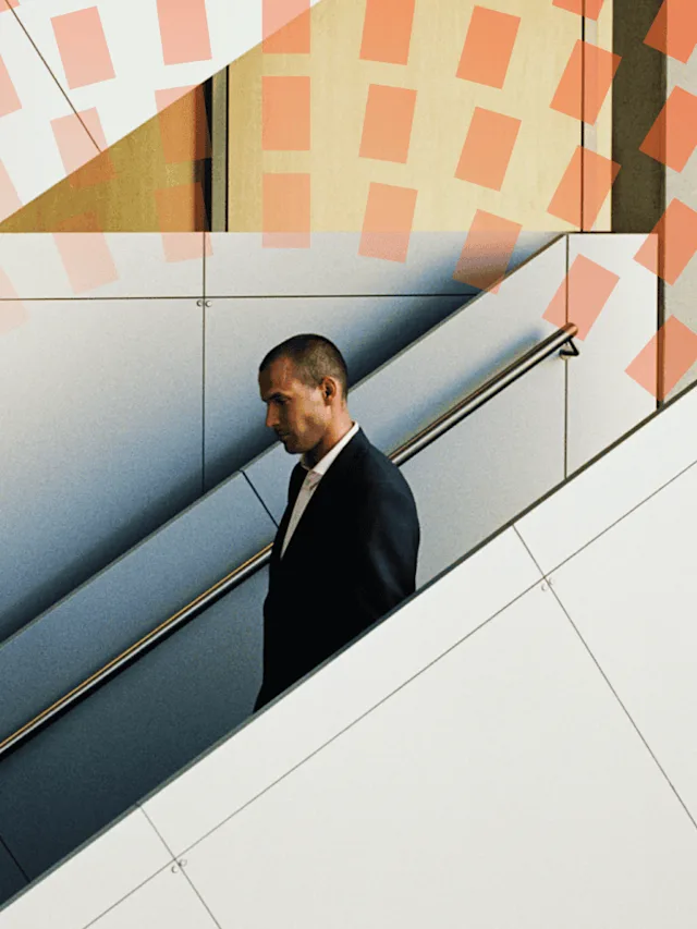A man in suit going down in an escalator.