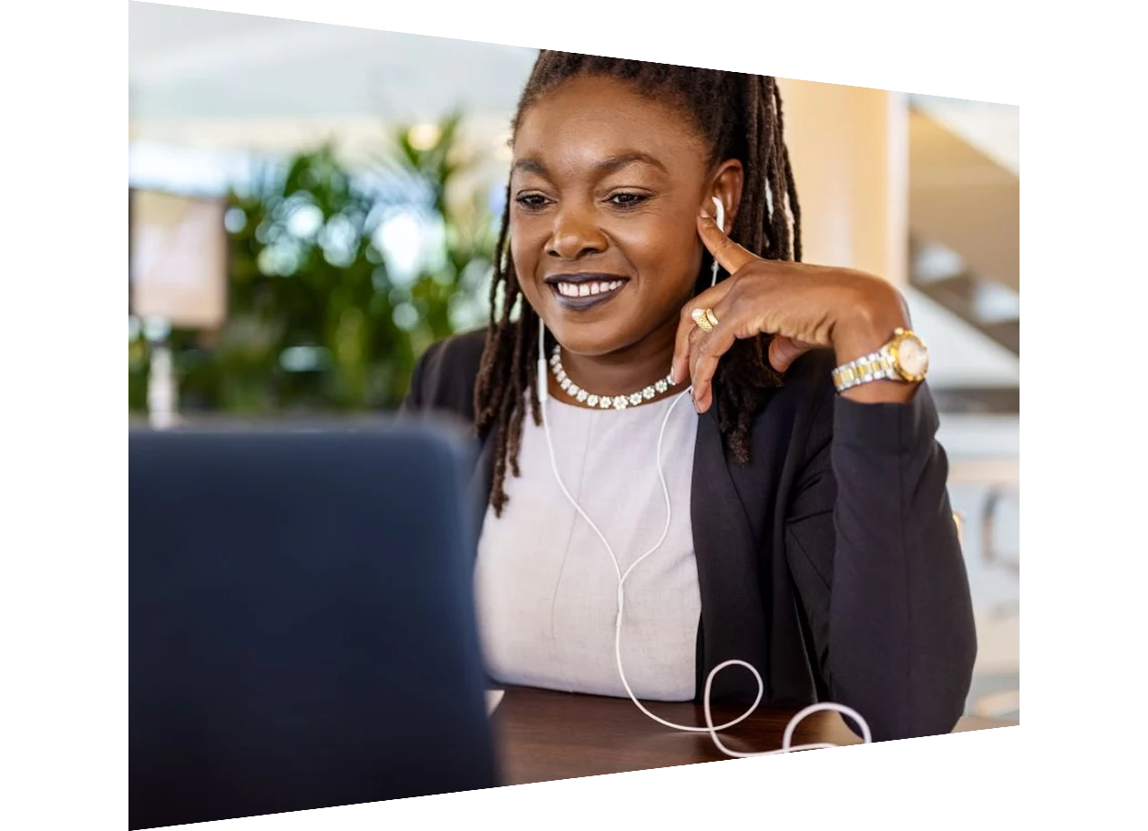 African woman wearing earplugs working on a laptop