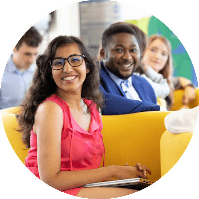 A man and woman sit together and smile at the camera.