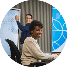One female and two male P&G employees collaborating in P&G workspace. Female employee and P&G logo are at center of image and male employees are to each side.