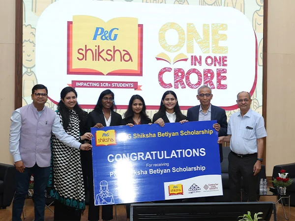 Group of scholarship recipients and presenters holding a P&G Shiksha Betiyan Scholarship congratulatory sign at an award ceremony in India.