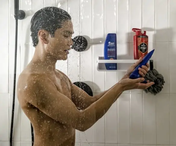 Man in shower squeezes Head & Shoulders shampoo into his hand.