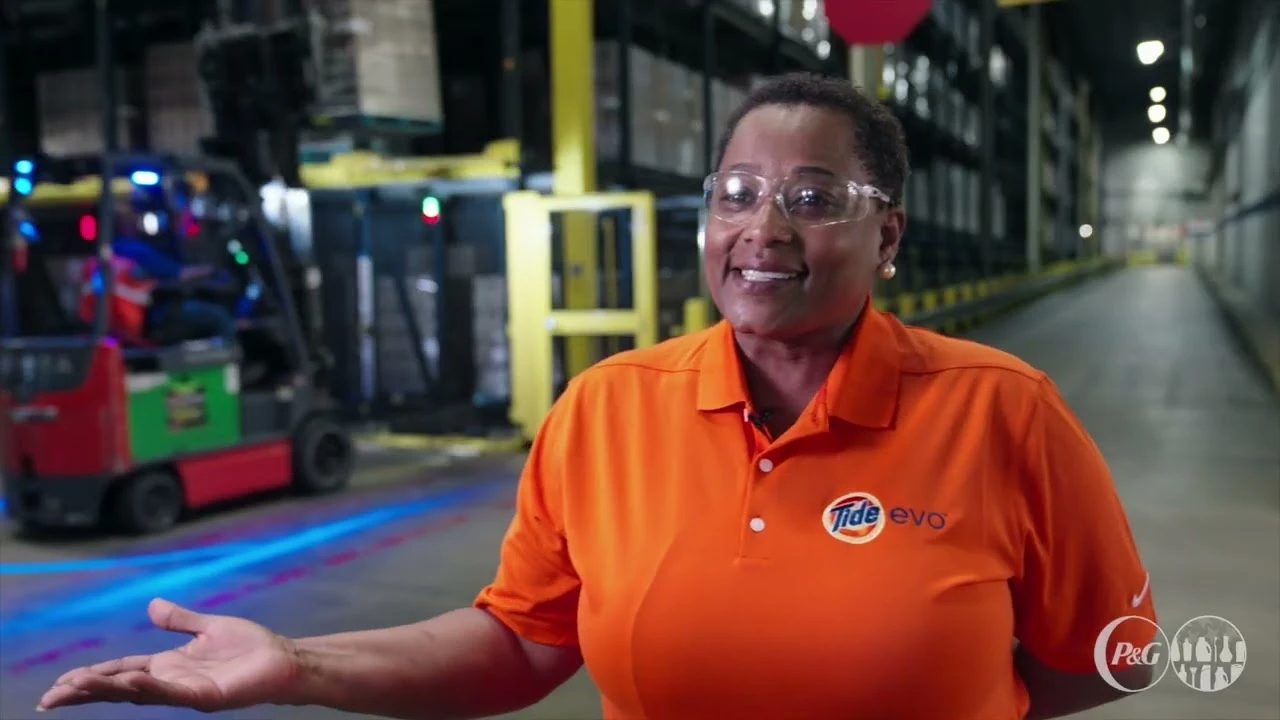Employee speaking in warehouse setting with pallets and packaging equipment