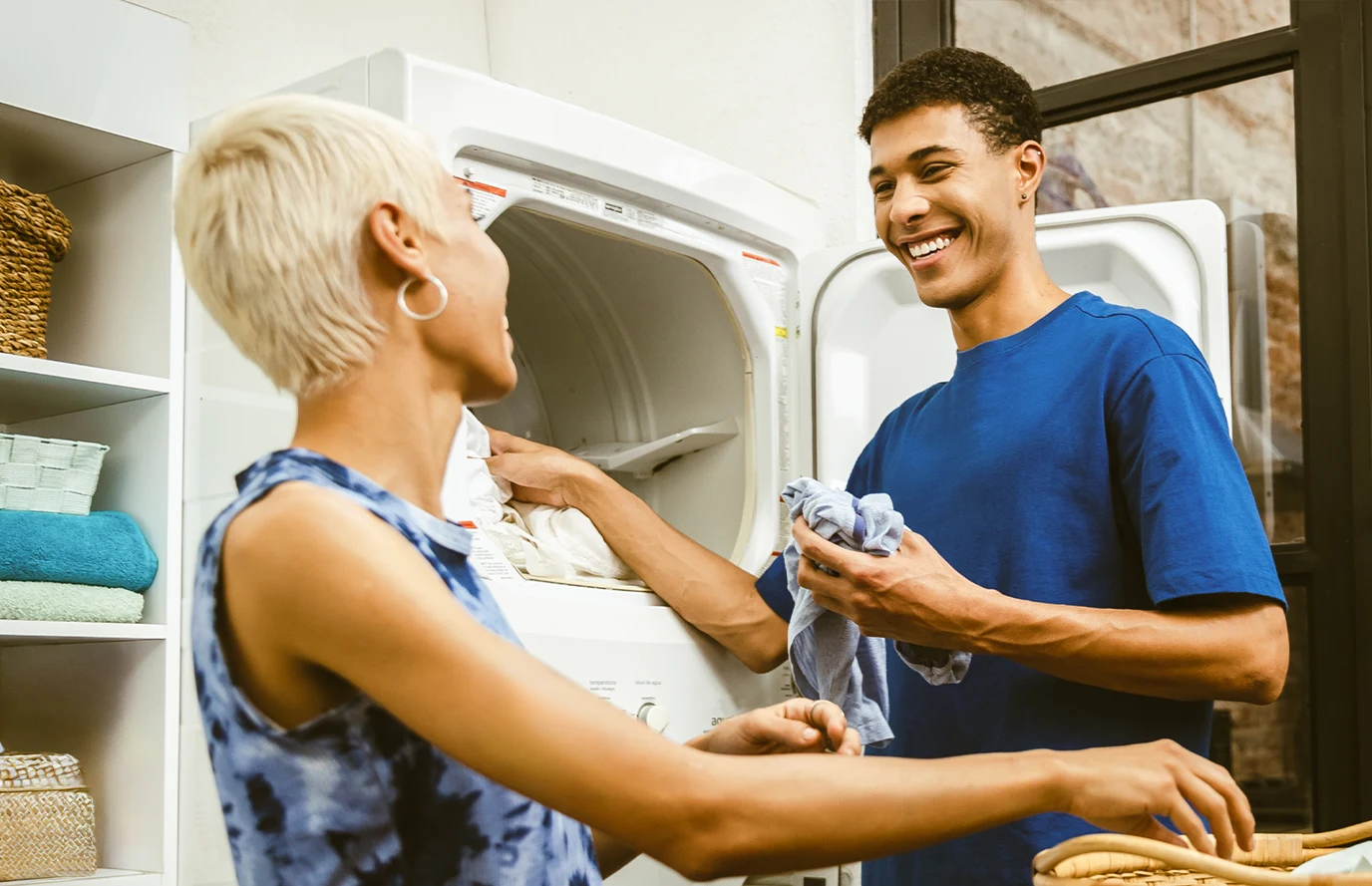 Man and woman doing laundry—he wears a blue shirt; she wears a blue tank top.