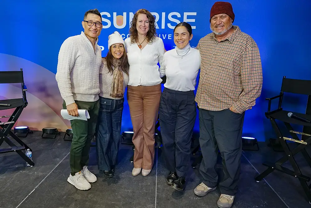 Five people stand side by side smiling in front of the Sunrise Collective backdrop.