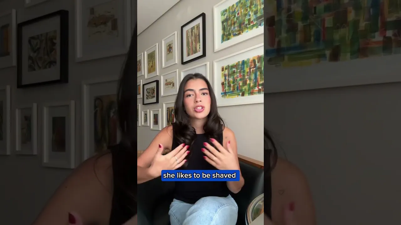 A Hispanic woman with long dark hair, a black sleeveless top and jeans. She sits in a living room.