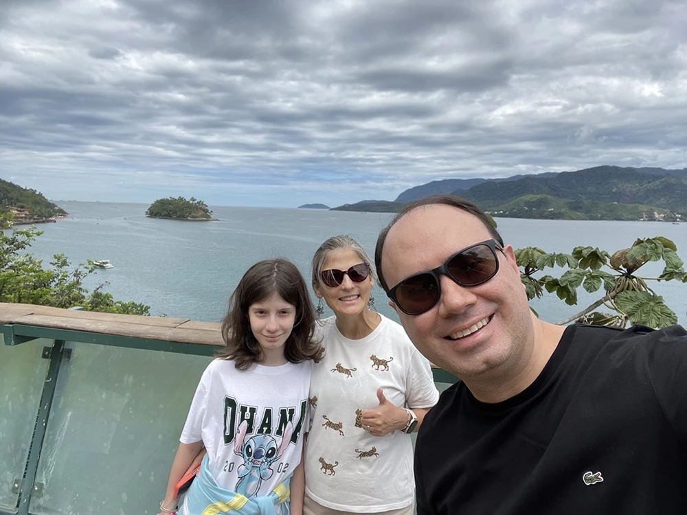 Man, woman and child posing for a photo in front of water.
