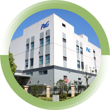 A white P&G office building with trees and a fence surrounding it.