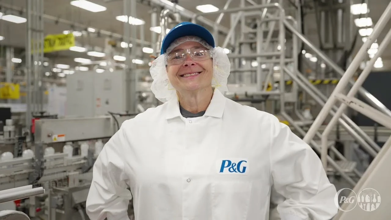 Employee in protective clothing standing near manufacturing equipment