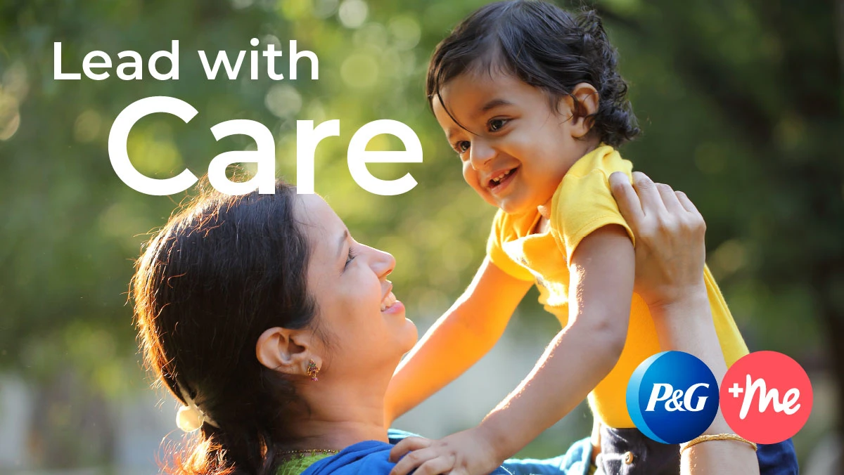 A woman with dark hair holds up her young son with short, curly dark hair. "Lead With Care" is written in white text in the upper left corner. The round blue P&G logo sits in the bottom right corner, next to a round pink circle with "+me" in white text.