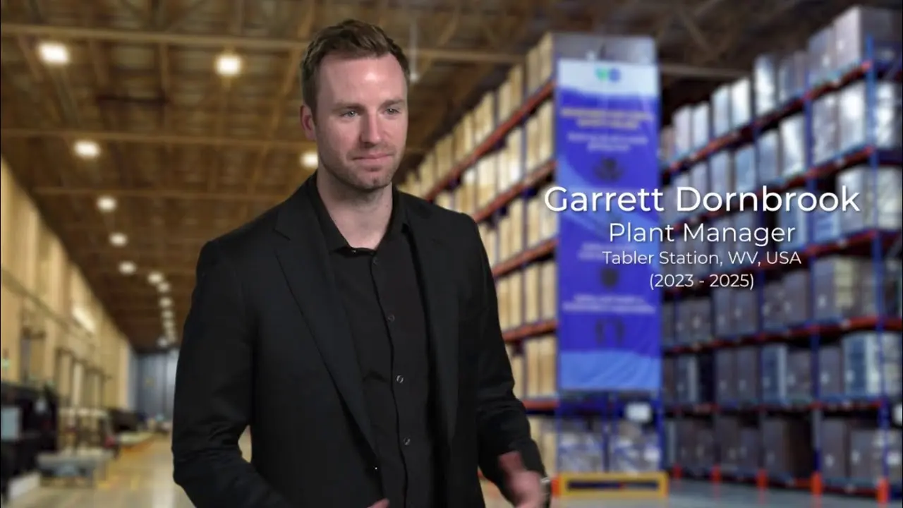 Plant manager in warehouse aisle with tall storage racks and stacked containers