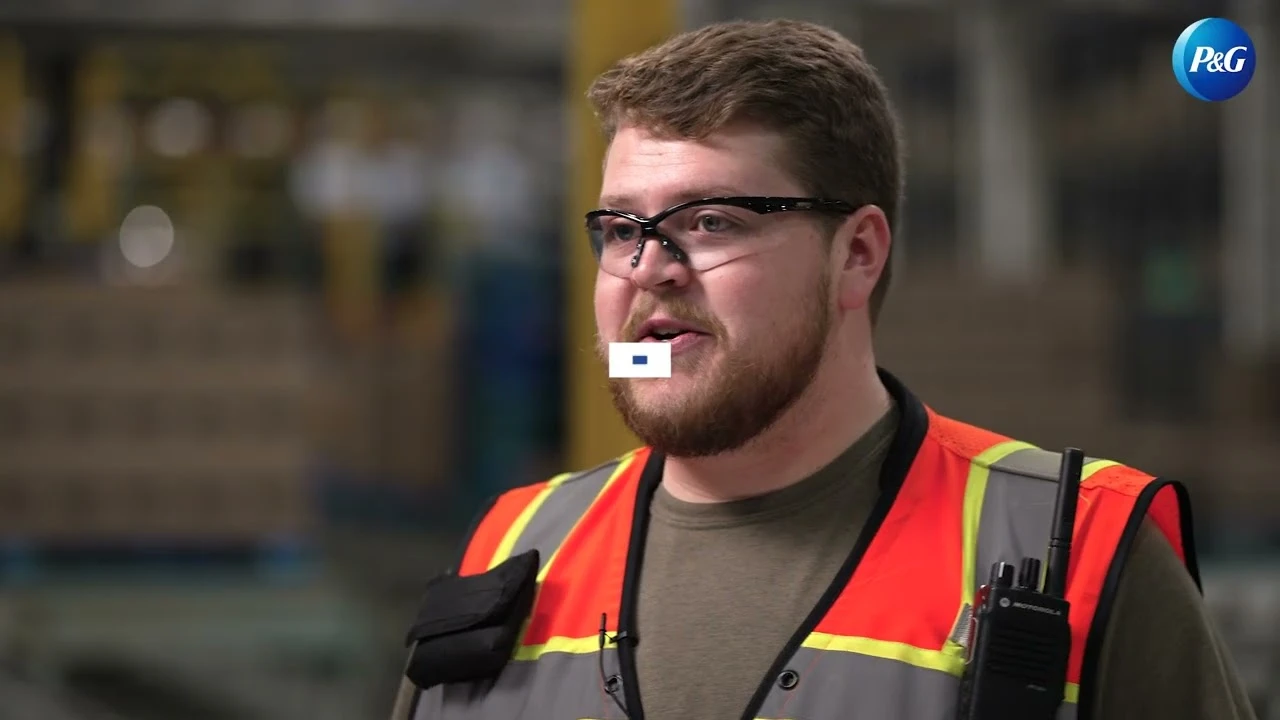 Employee wearing safety vest speaking in warehouse aisle with equipment