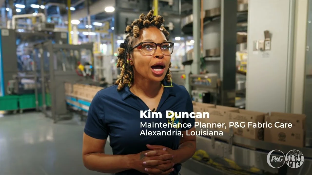 Employee speaking beside conveyor line moving packaged goods in manufacturing facility