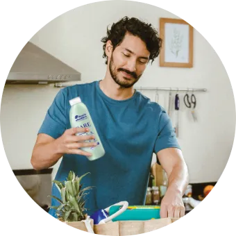 A man and woman are unpacking a bag of groceries, including Tide, Dawn and Metamucil.