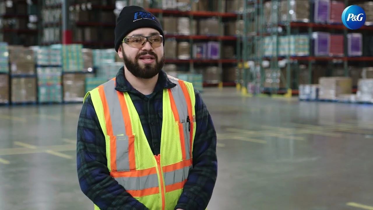 Employee wearing safety vest speaking in distribution area with storage racks