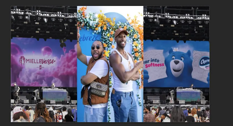 Two men are standing back to back, smiling and facing the camera, with a heart-shaped flower arrangement behind them.