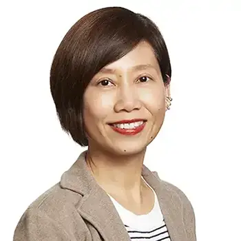 Professional headshot with a light background of a smiling woman with straight brown hair parted at the side wearing a tan jacket with white shirt.