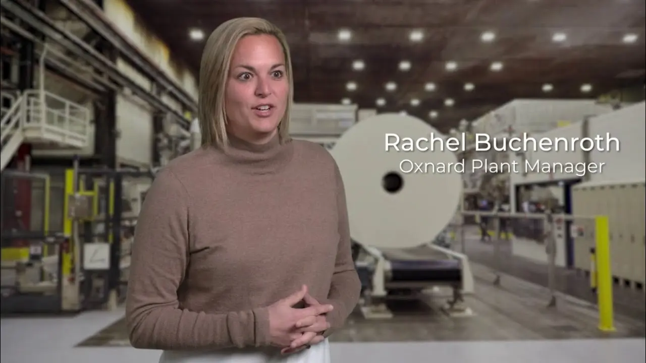Plant manager speaking near large paper roll machine in production facility
